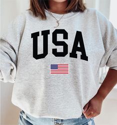 USA Flag Sweatshirt, USA Flag gifts, 4th of July Shirt, july, 4th sweatshirt, usa sweatshirt, American flag sweatshirt How to Order 1* View all color and size charts before you place your order. 2* Select your shirt "SIZE" and "COLOR". 3* Click add to cart.  If you are ordering more than 1 item, you need to repeat this process for each item you wish to order. Product Information Gildan Hoodie- Sweatshirt 8 oz.(US) 13.3 oz.(CA), 50/50 preshrunk cotton/polyester Heather Sport colors: 60/40 polyester/cotton Air jet yarn = softer feel and reduced pilling Double needle stitching at shoulder, armhole, neck, waistband and cuffs 1 x 1 rib with spandex Quarter-turned to eliminate center crease Safety Green: Compliant with ANSI / ISEA 107 Tearaway label Washing Care Instructors Use cold water when w American Flag Sweatshirt, Usa Sweatshirt, Gildan Hoodie, 4th Of July Shirt, Sweatshirt Women, Usa Flag, Size Charts, July 4th, Grey Sweatshirt