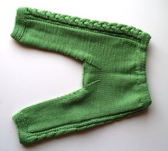 a green knitted leg warmer on a white surface