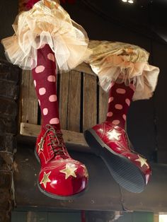 two pairs of red and white polka dot shoes hanging from a wooden beam in front of a brick wall