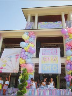 people standing in front of a building with balloons and streamers all over the place