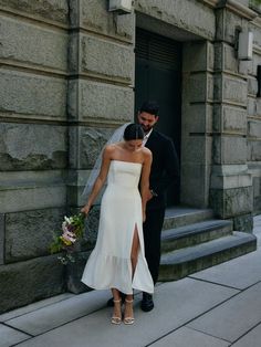 a bride and groom standing in front of a building