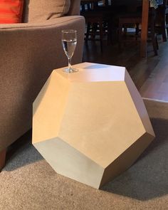 a wine glass sitting on top of a wooden table next to a couch in a living room