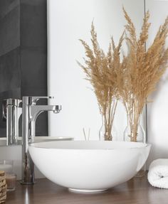 a white bowl sink sitting on top of a wooden counter next to a bathroom faucet