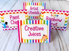 three colorful business cards sitting on top of a white wooden table next to each other