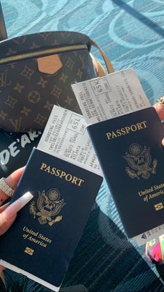 two people holding up their passport cards in front of a handbag and luggage bag