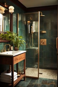 a bathroom with green tile and gold fixtures on the shower door, sink, and mirror