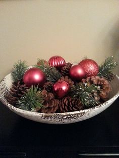 a bowl filled with christmas ornaments and pine cones