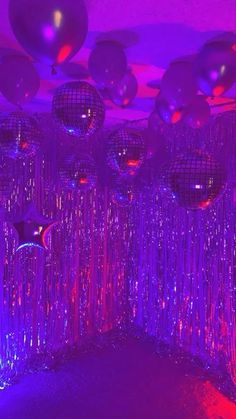 disco balls and streamers are hanging from the ceiling in this purple room with black lights