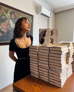 a woman standing next to stacks of books