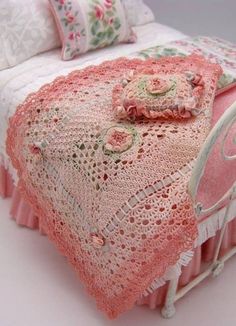 a doll bed with pink bedspread and pillows