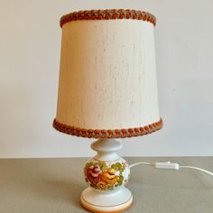 a lamp that is on a table with a white base and orange trim around it