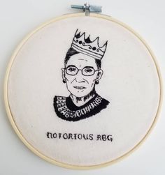 embroidered portrait of an old woman with glasses and a crown on her head