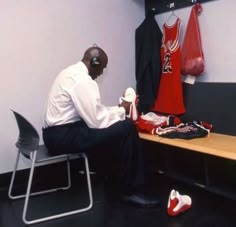 a man sitting on a bench in front of a basketball jersey and other sports items