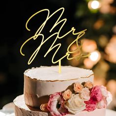 there is a cake with flowers on it and the word mr and mrs spelled in gold