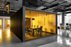 an office with yellow glass walls and black chairs in the center, along with large windows on both sides