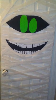 a door decorated with white paper and green eyes