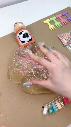 a person's hand on a table next to some crafting supplies and crafts