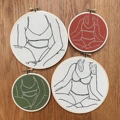 three embroidery hoop art pieces on a wooden surface with one woman's torso in the center