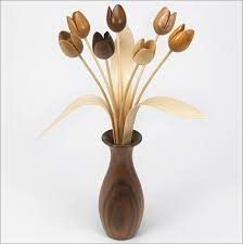 a wooden vase filled with flowers on top of a white table