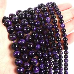 purple and black beads are being held in someone's hand