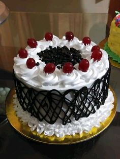 a black and white cake with cherries on top is sitting on a gold plate