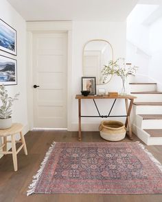 a living room with a rug, table and mirror on the wall next to stairs