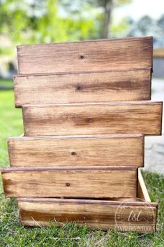 three wooden boxes stacked on top of each other in the grass