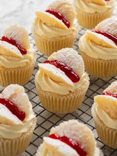 some cupcakes with icing and powdered sugar on top are sitting on a cooling rack