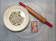 a paper plate with a drawing on it next to a wooden spoon and small stamp