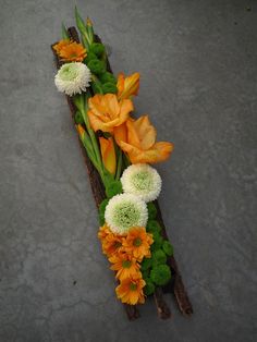 an arrangement of flowers is arranged on a piece of wood