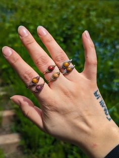 Handmade Adjustable Wire Wrapped Gemstone Rings/ Beaded Rings/ Gemstone Ring/ Birthsone Jewelry/ Unique Jewelry/ Stackable Rings 🖤✨Choose a band that's adornably you. Just pick a metal type and enter your ring size and I'll size them to fit just right! Plus, They are adjustable so don't worry if you don't know your exact size✨ 🖤  Due to the natural variations in gemstones , the colors of each stone may differ slightly from what is pictured. It's a feature not a flaw 💗 🤘METAL INFO BRASS Brass jewelry is budget-friendly and built to last. Made from copper and zinc, it gives a warm gold shine without the price tag of real gold. Brass is resistant to corrosion and rust. It's tougher than silver and won't wear off like plated metals. Over time, Brass will develop a unique vintage patina, ma Adjustable Bohemian Rings With Stones, Bohemian Adjustable Rings With Stones, Adjustable Brown Ring Jewelry, Brown Natural Stone Ring, Brown Natural Stone Rings, Adjustable Brown Gemstone Rings, Mookaite Jasper, Argentium Silver, Wire Wrapped Rings