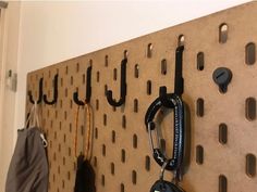 there is a coat rack with hooks and umbrellas hanging on the pegboard next to it