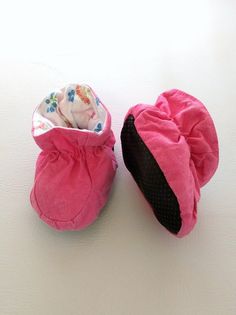 two pairs of pink baby shoes sitting on top of a white table