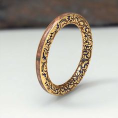 an intricately designed gold ring on a white surface