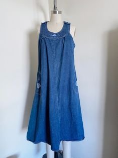 "70's embroidered denim dress. Features a flared style, side pockets, embroidery, medium weight denim, midi length, non functioning shoulder buttons, back button closure, and a loose fit.  Label: None Size Marked: None Estimated Size: Loose Medium Material: 100% Cotton   Color: A bit darker than photographed  Condition: Excellent, some areas of wear Measurements:     Chest: 19 1/2\"     Waist: 21\"     Hips: 25\"      Length: 43 1/2\" Measured flat, Please double width measurements for total. Pl Casual Embroidered Medium Wash Denim Dress, Retro Cotton Denim Dress With Pockets, Medium Wash Cotton A-line Denim Dress, Vintage Medium Wash Denim Dress With Pockets, Vintage Denim Blue Knee-length Dress, Vintage Knee-length Denim Blue Dress, Retro Summer Cotton Denim Dress, Vintage Knee-length Denim Dress For Summer, Casual Medium Wash Denim Dress With Floral Embroidery