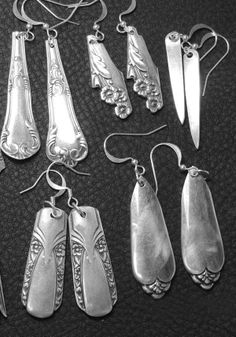 six pairs of silver earrings on a black surface