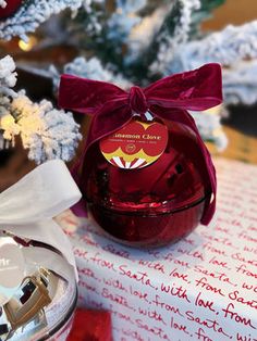 a red glass jar with a bow on it sitting next to a christmas tree and other decorations