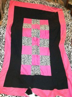 a pink and black quilt sitting on top of a bed