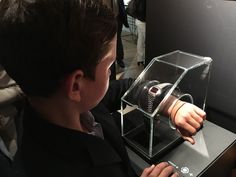 a young boy looking at an object in a glass case with headphones on it