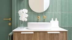 a white sink sitting under a bathroom mirror next to a wooden cabinet with flowers on it