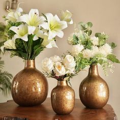 three vases with flowers in them sitting on a table