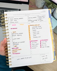 a person holding up a notebook with notes on it next to a laptop and keyboard