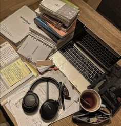 a table topped with books and headphones on top of a laptop computer next to a cup of coffee