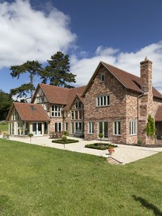 a large brick house sitting in the middle of a lush green field on a sunny day