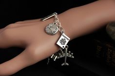 "A collection of silver plated travel and tourism themed charms have been dispersed around a shimmering silver plated bracelet chain in this handmade charm bracelet. This world traveler charm bracelet is then completed with a lobster clasp and a 1/2 inch of chain at the end for adjustable sizing. Charms in this bracelet include an airplane charm, passport charm, \"find joy in the journey\" charm, world charm, camera charm, \"bon voyage\" charm, suitcase charm, binoculars charm, and compass charm Silver Metal Jewelry For Travel, Adjustable Silver Jewelry For Travel, Nickel-free Silver Bracelets As Souvenir, Silver Nickel-free Bracelet Souvenir, Camera Charm, Find Joy In The Journey, Travel Bracelet, Handmade Charm Bracelets, Joy In The Journey