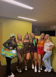 four young women posing in front of a yellow wall