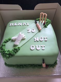 a cake that is decorated with green frosting and white icing, including cricket equipment