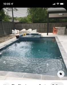 an empty swimming pool in a backyard with lounge chairs and tables around the pool area