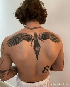 a man with tattoos on his back is standing in front of a mirror