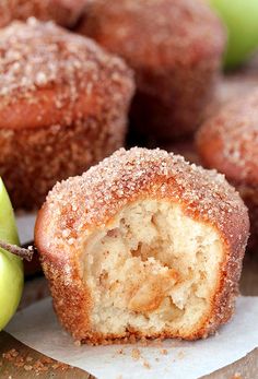 an apple and some sugar covered doughnuts on a table